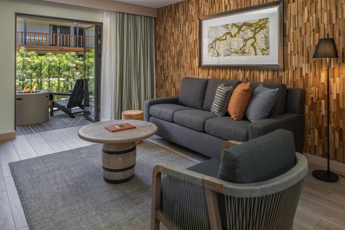 Ein modernes Wohnzimmer mit grauem Sofa, rundem Couchtisch und einem gerahmten Kunstwerk an der Wand.