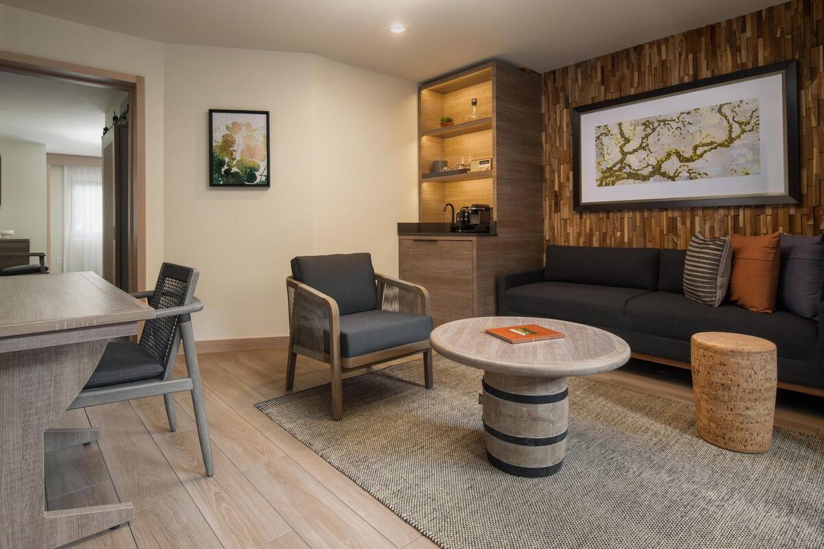 Ein modernes Wohnzimmer mit Essbereich, einer Couch, einem Couchtisch und einer Holzkabine.