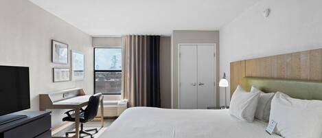 Une chambre d’hôtel équipée d’un lit, d’un bureau, d’une chaise, d’une télévision et d’une fenêtre avec des rideaux.