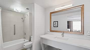 A modern bathroom with a bathtub, toilet, and vanity with a mirror.