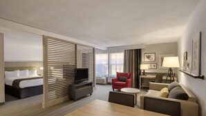 Una habitación de hotel con cama, televisión, escritorio, silla, sofá y mesa de comedor.