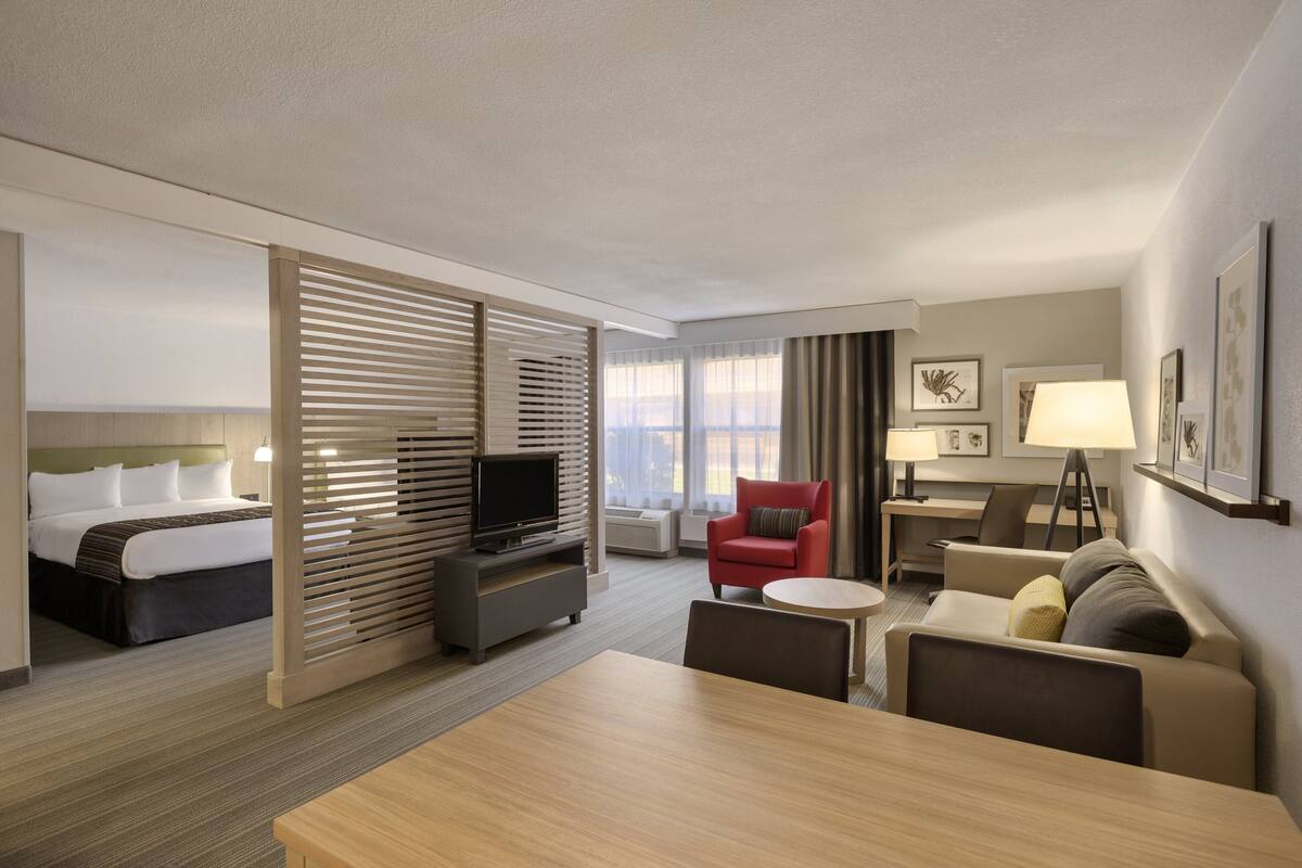 Une chambre d’hôtel équipée d’un lit, d’une télévision, d’un bureau, d’une chaise, d’un canapé et d’une table à manger.