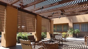 Un patio al aire libre con mobiliario de mimbre, una chimenea y una pérgola.