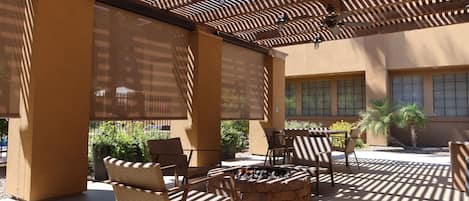 Un patio al aire libre con mobiliario de mimbre, una chimenea y una pérgola.