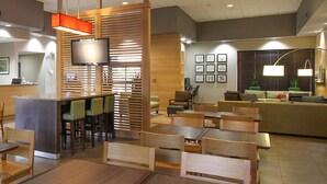 Un moderno vestíbulo de hotel con muebles de madera, una recepción y una pantalla de televisión.