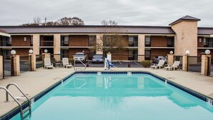 A swimming pool with lounge chairs and a building with multiple balconies in the background.