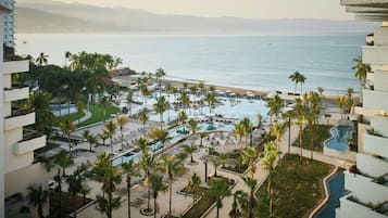 Alberca techada, alberca al aire libre y sombrillas en la alberca