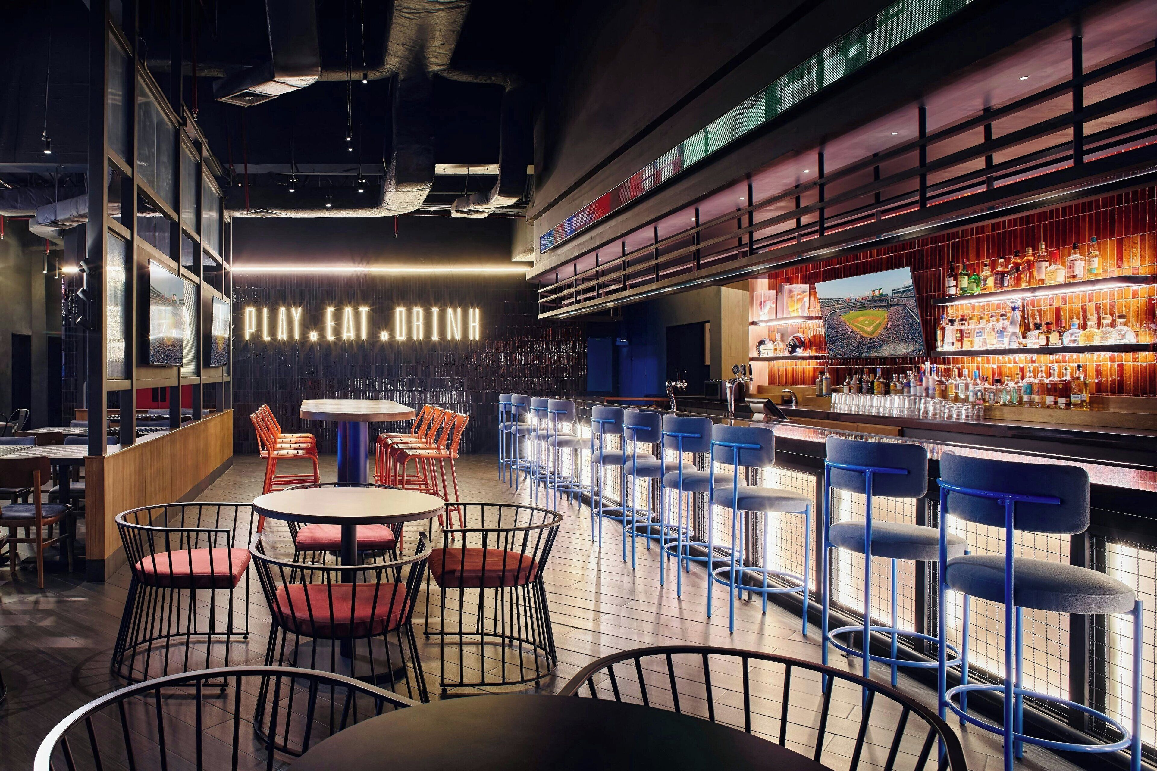 Un área de bar moderna con un letrero de neón, taburetes y una variedad de botellas de licor.