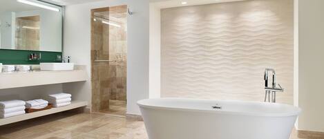 A modern bathroom with a freestanding bathtub, a large mirror, and a shower area.