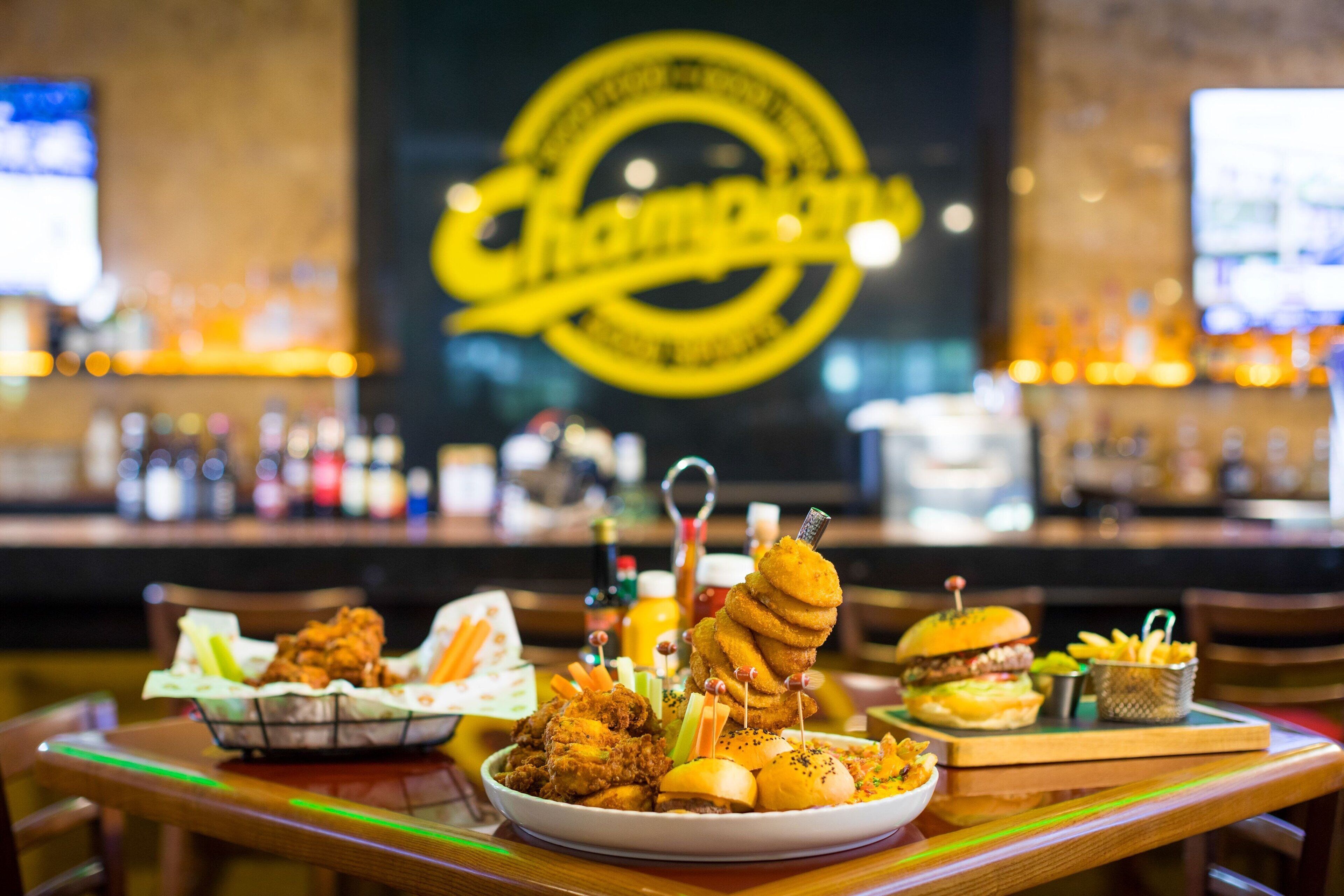 Une table de restaurant avec divers plats frits et un hamburger.