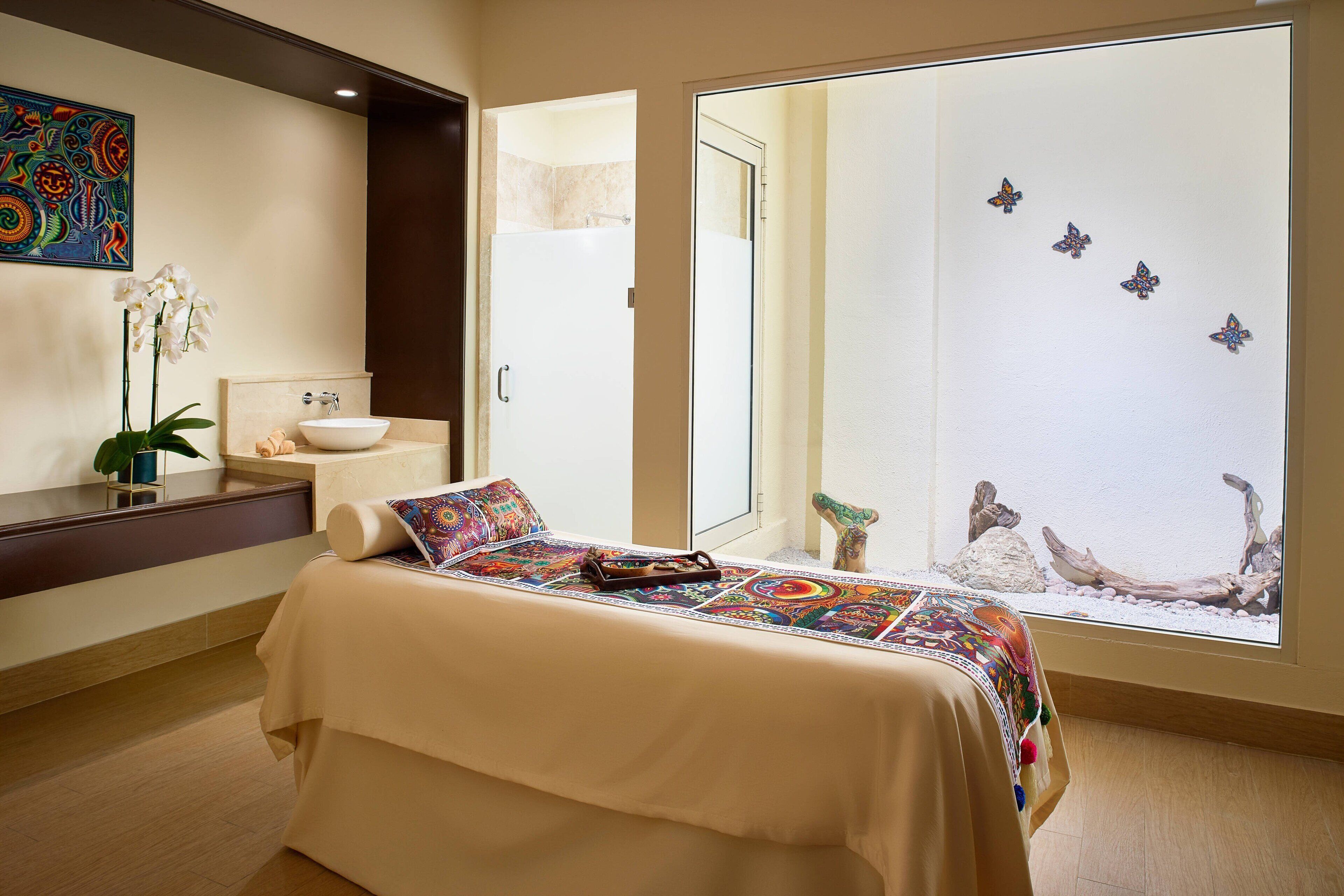 A hotel room with a bed, a bathroom, and a large window with a view of the beach.