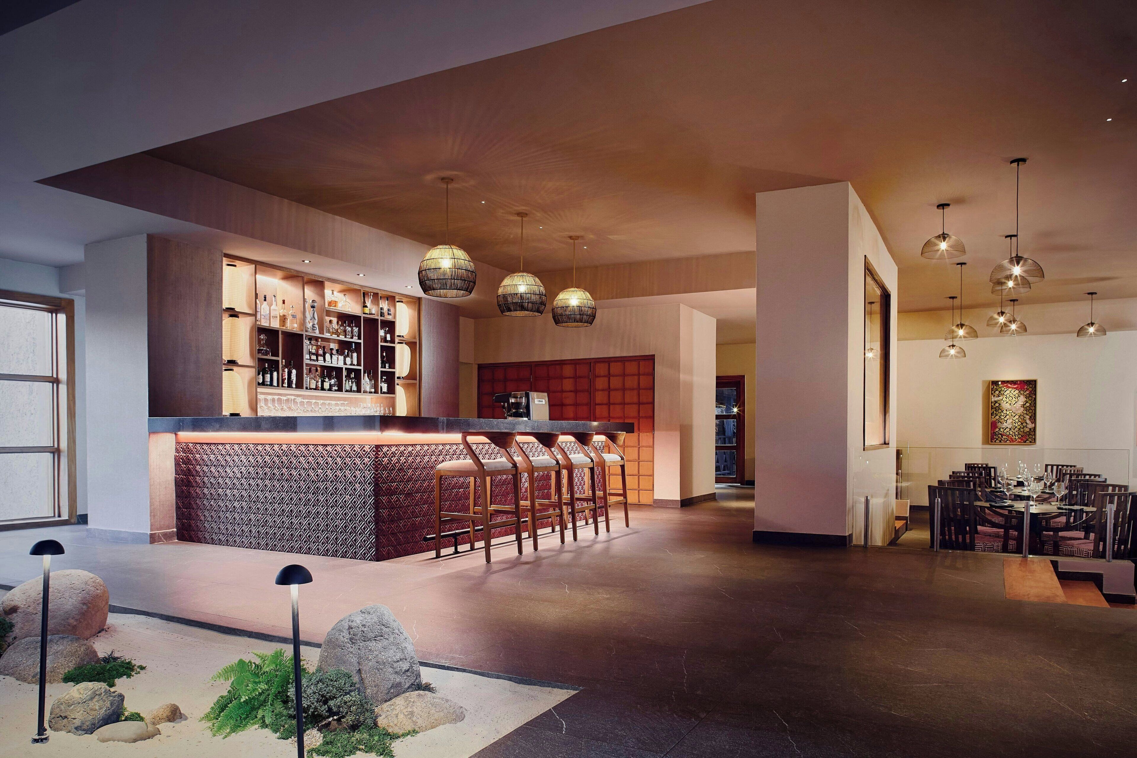 A modern bar area with a counter, bar stools, and pendant lighting.