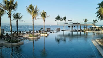 Alberca techada, alberca al aire libre y sombrillas en la alberca