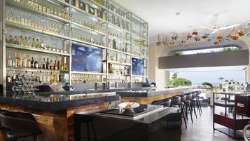 A modern bar with a high bar counter, multiple seating areas, and a large display of liquor bottles.
