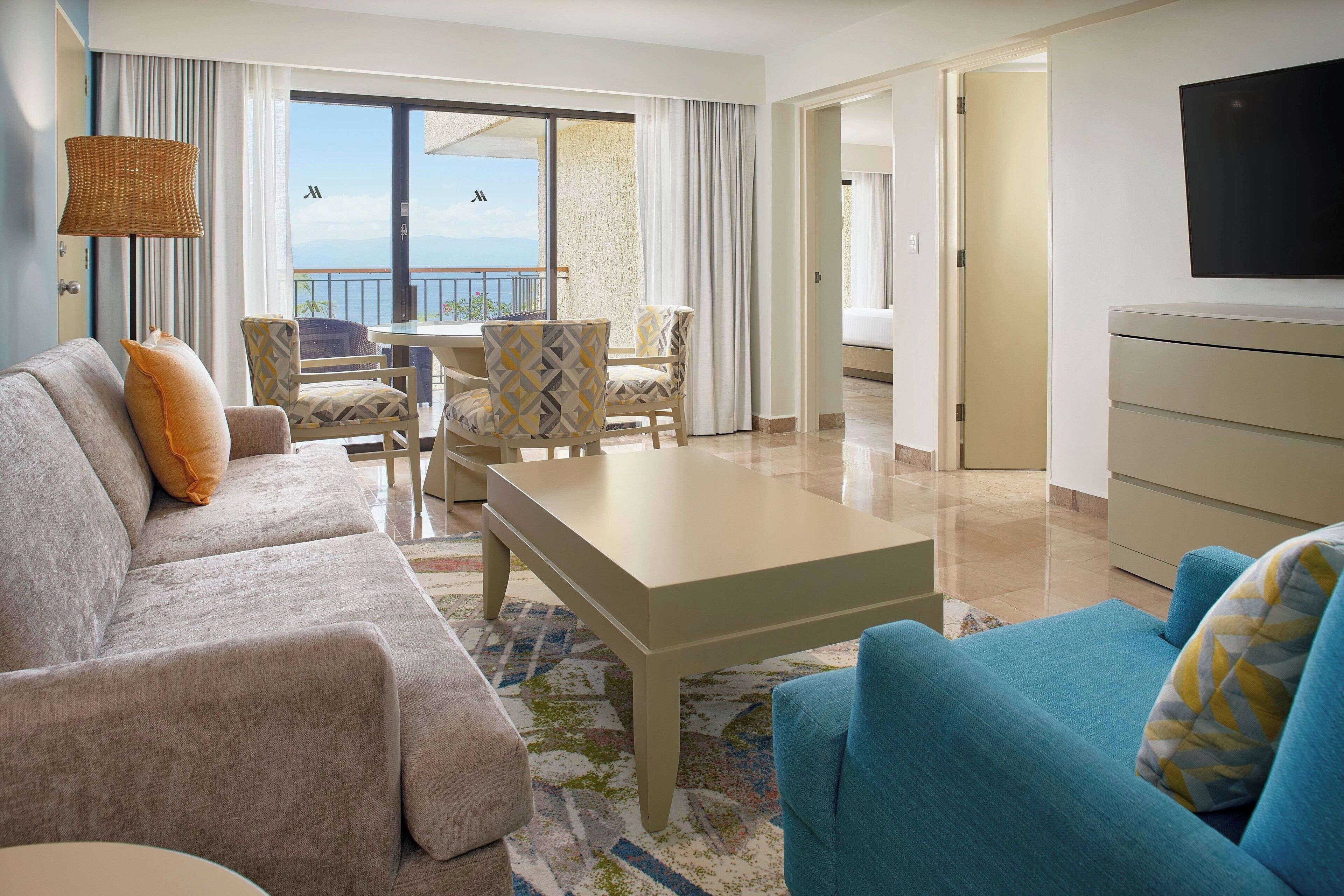 A hotel room with a sofa, armchairs, a coffee table, and a TV.