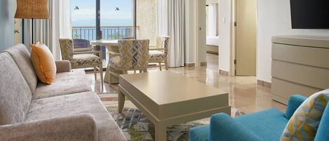 A hotel room with a sofa, armchairs, a coffee table, and a TV.