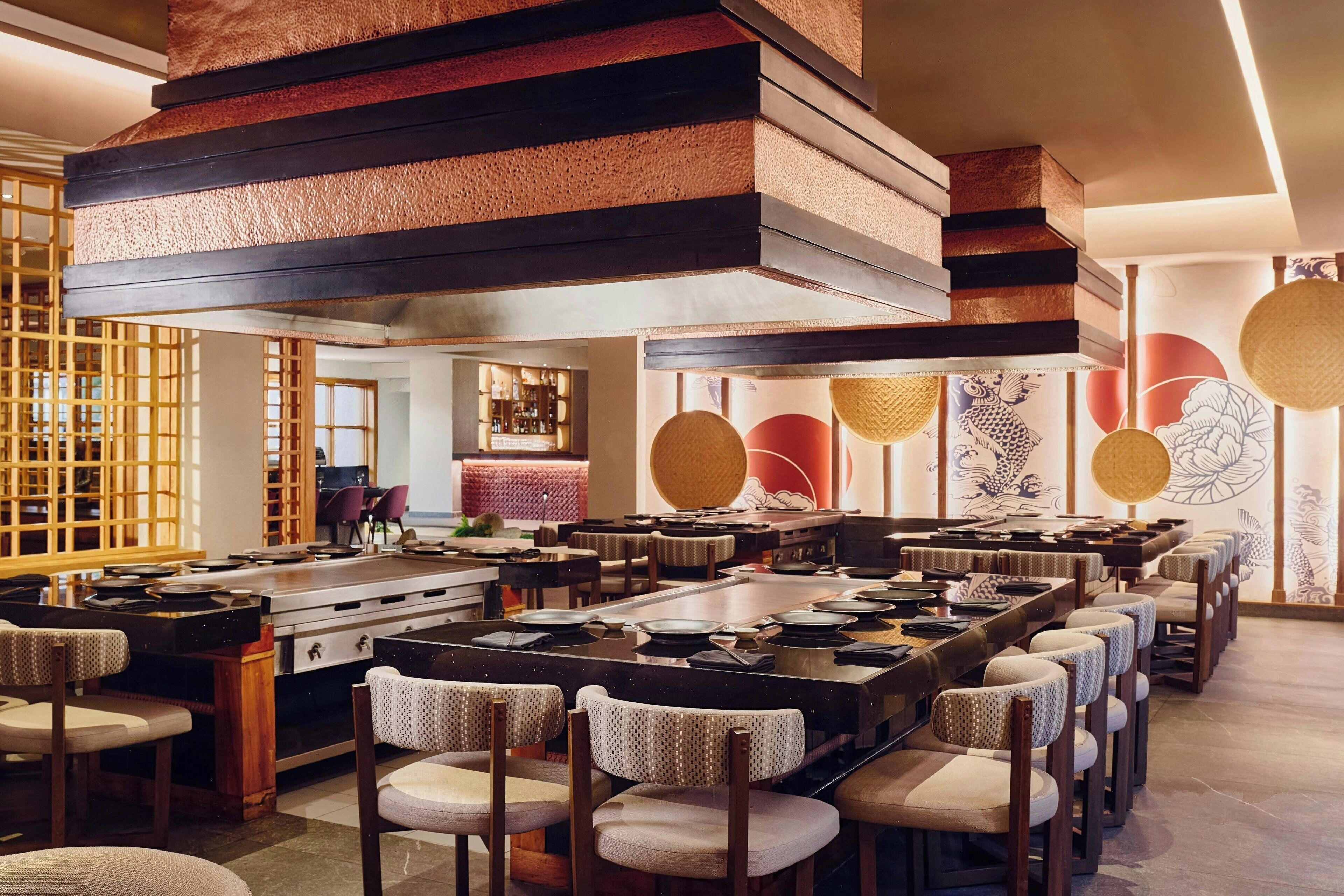 A restaurant with a long communal table, individual seating, and a traditional decor style.
