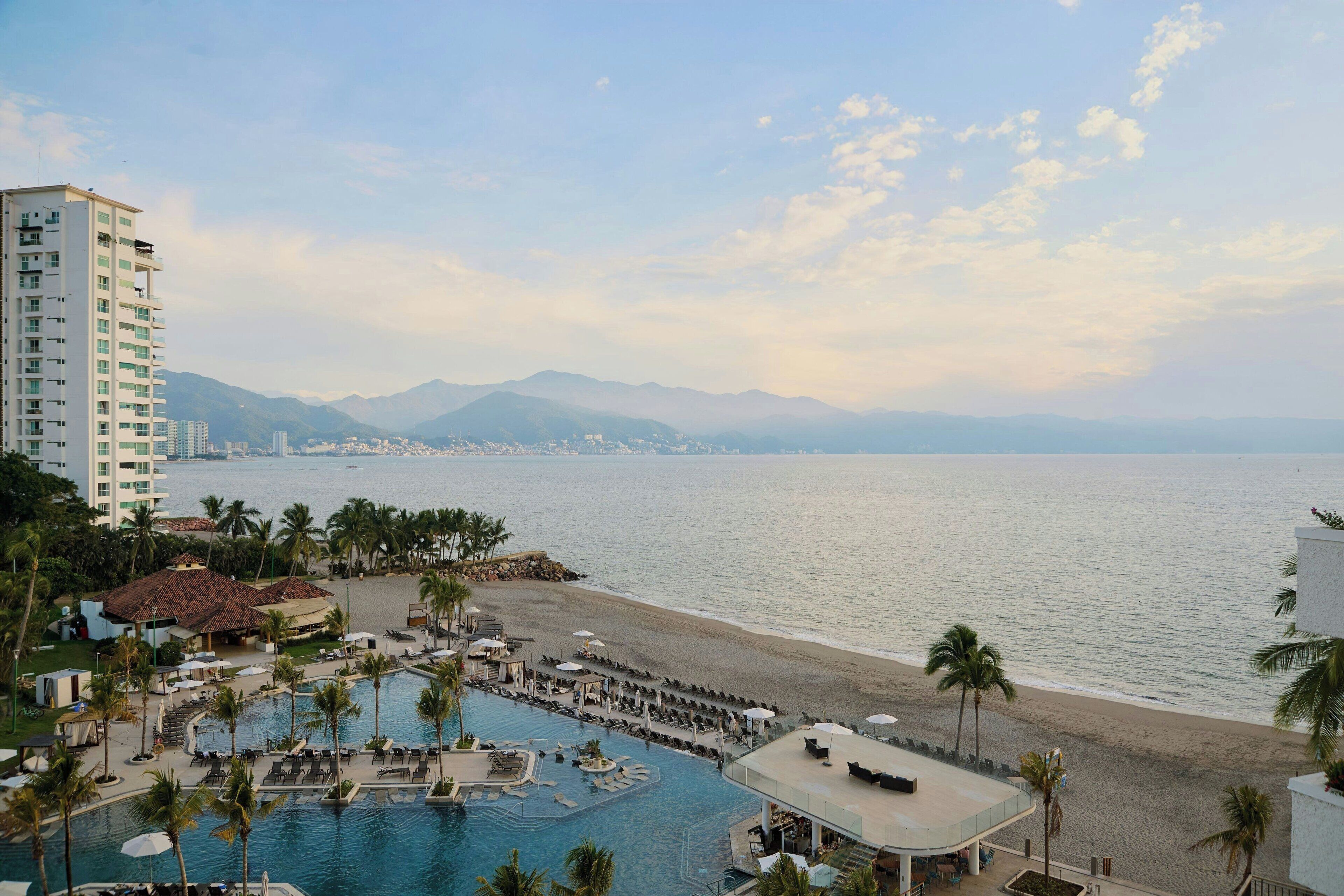 Un complexe hôtelier doté d’une piscine, d’un accès à la plage et offrant une vue sur les montagnes.