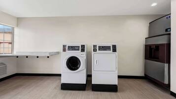 A laundry room with two front-loading washing machines, a built-in water cooler, and a window providing natural light.