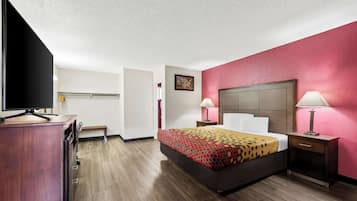 A hotel room with a bed, bedside tables, a desk, and a television.