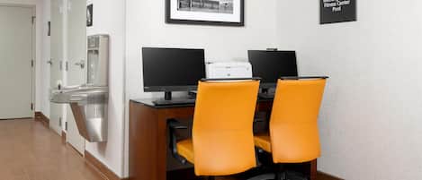 Un bureau d’hôtel équipé de deux bureaux, de deux chaises, d’une imprimante et d’un distributeur d’eau.