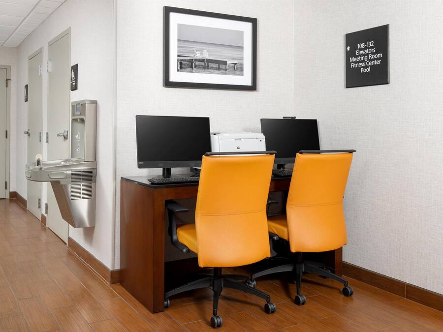 A hotel office with two desks, two chairs, a printer, and a water dispenser.
