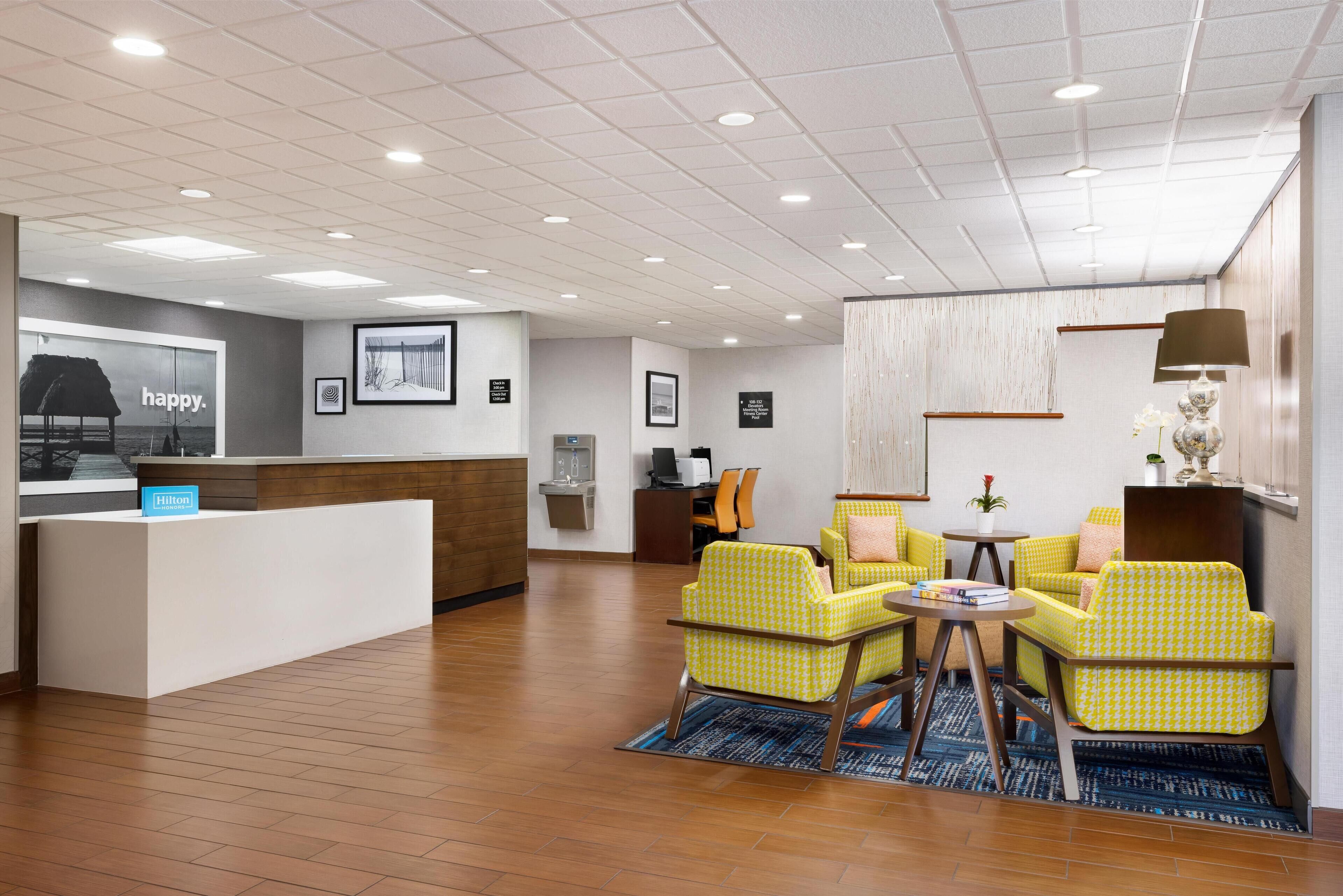 A hotel lobby with a reception desk, seating area, and framed pictures on the walls.