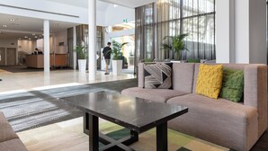 Eine moderne Lobby mit einer Couch, einem Couchtisch und einer Rezeption.