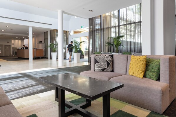 A modern lobby with a sofa, a coffee table, and a reception desk. - Holiday Inn Sydney Potts Point by IHG (Potts Point)
