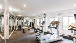 Ein Fitnessstudio mit Laufbändern, Kraftgeräten und Spiegeln.