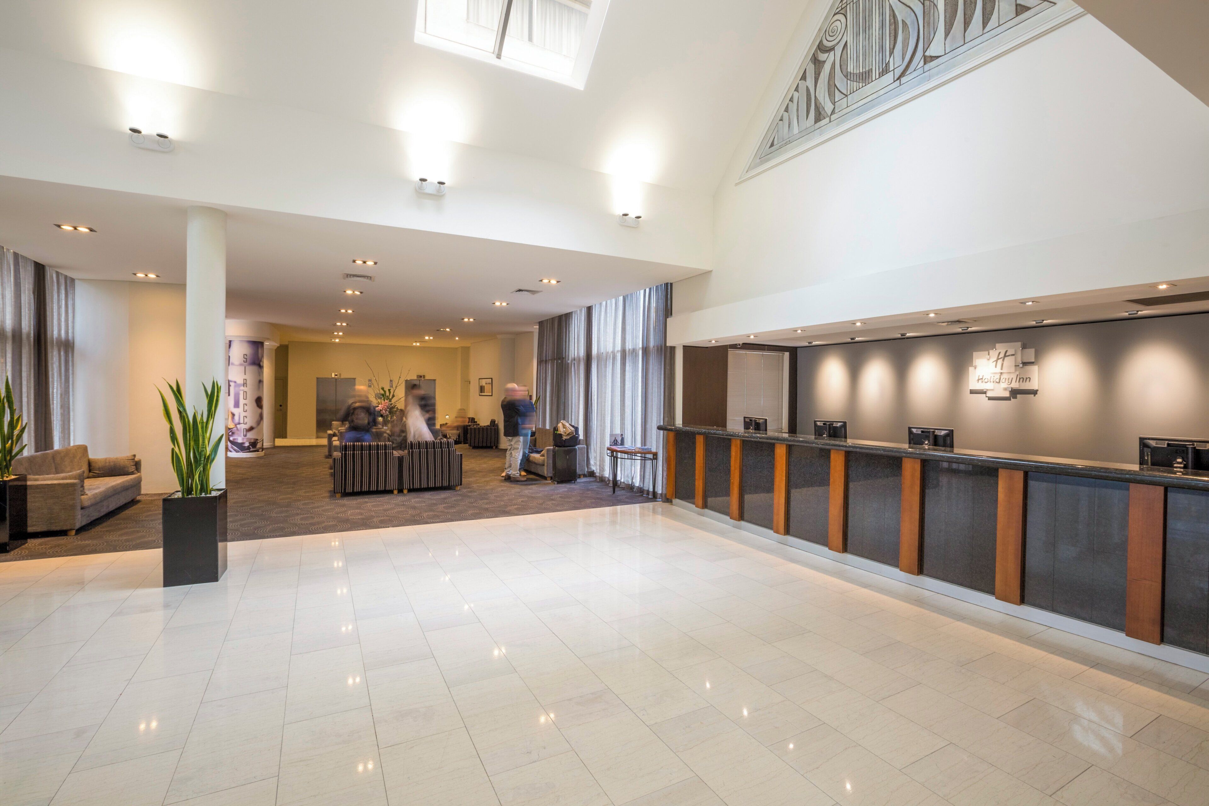 A spacious lobby with a reception desk, seating area, and a large window.