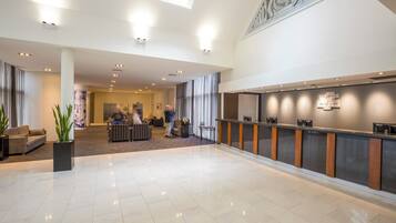 A spacious lobby with a reception desk, seating area, and a large window.
