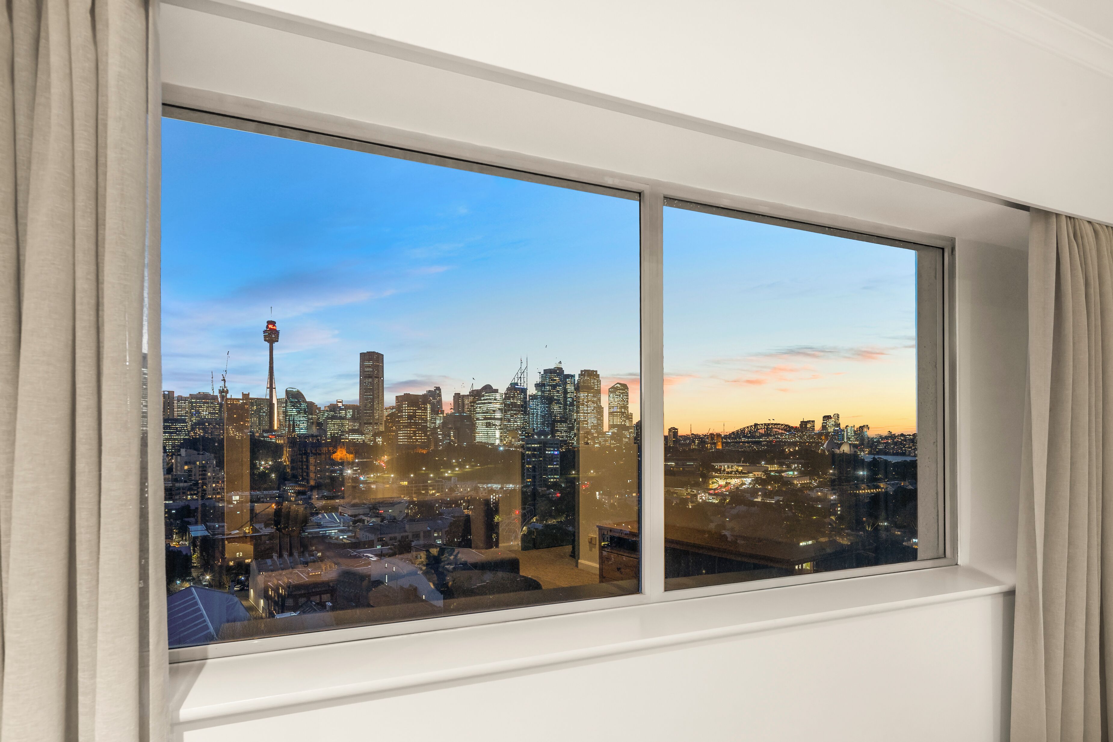 A cityscape view from a window with curtains.