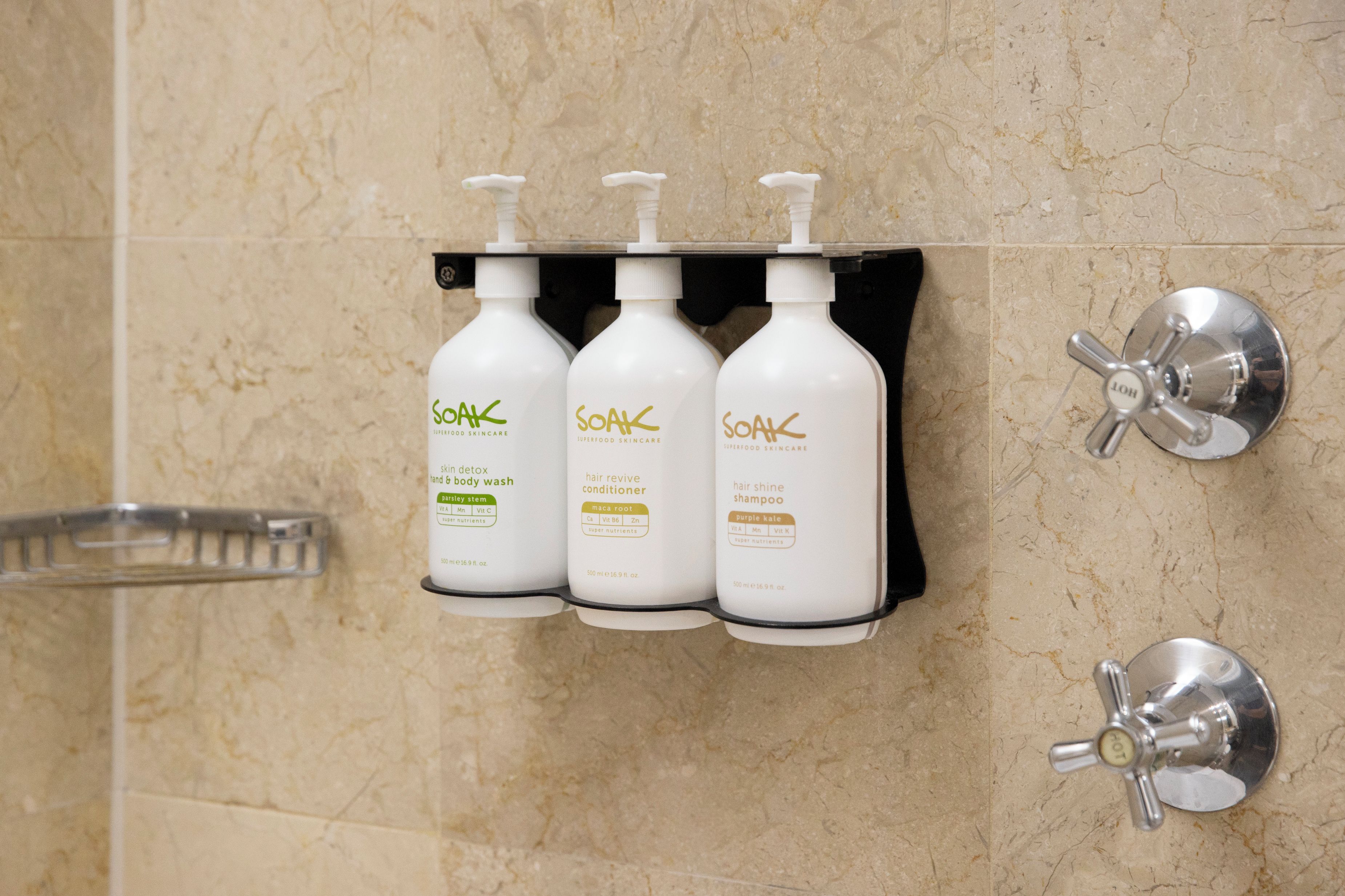A bathroom with three bottles of Soak Superfood Skincare products on a wall-mounted rack.