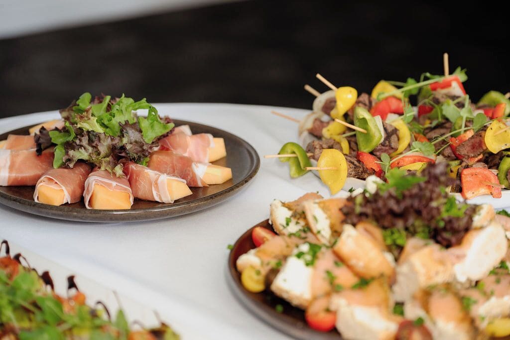 A table with various food items, including skewers and wrapped cheese.