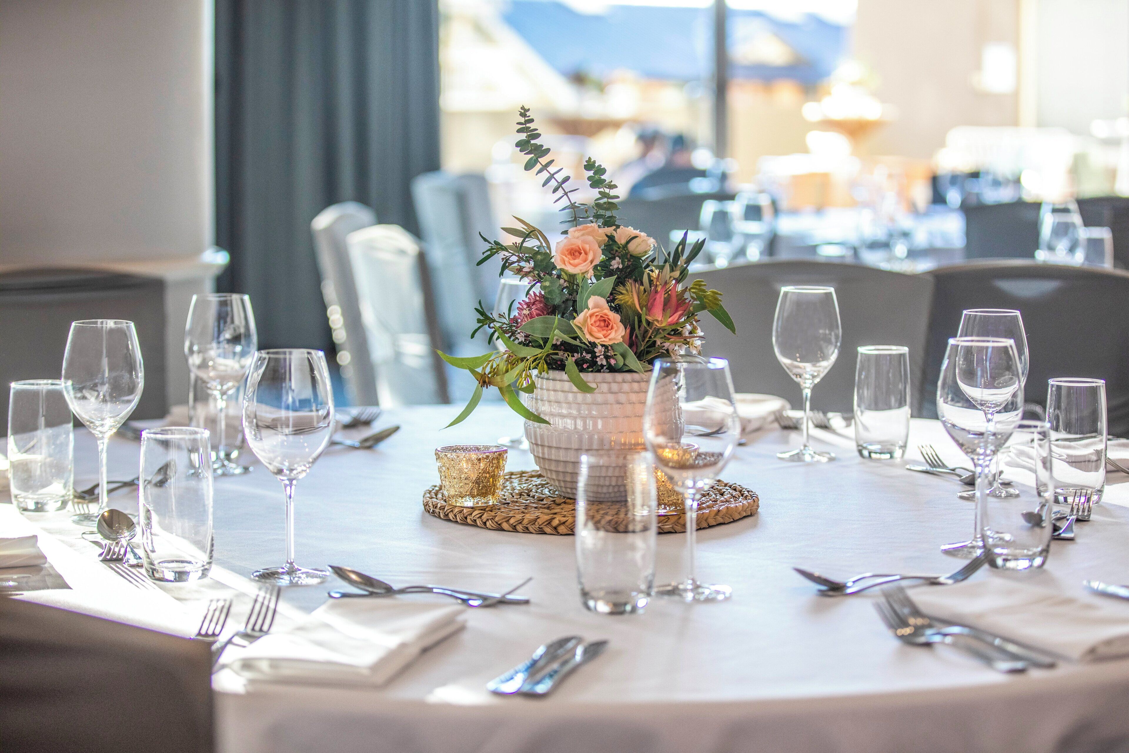 A dining table set with multiple wine glasses, cutlery, and a centerpiece with flowers.