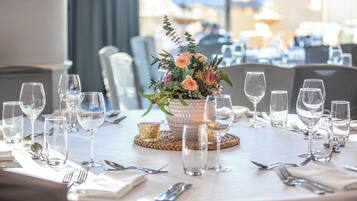 A dining table set with multiple wine glasses, cutlery, and a centerpiece with flowers.