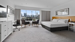 A hotel room with a bed, desk, chairs, and a city view. - Holiday Inn Sydney Potts Point by IHG (Potts Point)