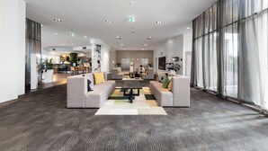 Eine geräumige Lobby mit einer zentralen Sitzgruppe, großen Fenstern und einem modernen Design.