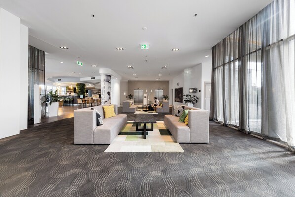 Eine geräumige Lobby mit einer zentralen Sitzgruppe, großen Fenstern und einem modernen Design.
