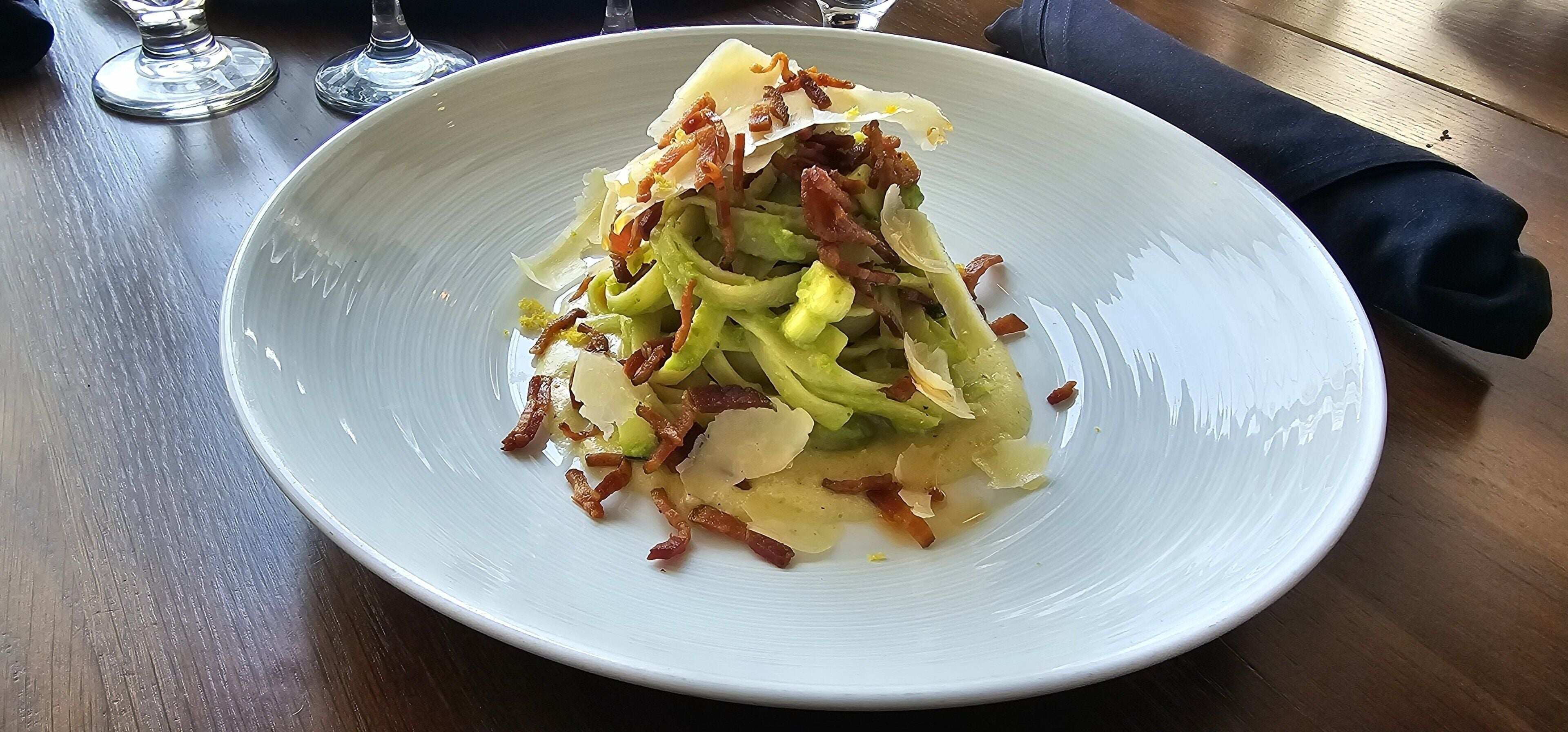 Un plato blanco con ensalada sobre una mesa de madera.