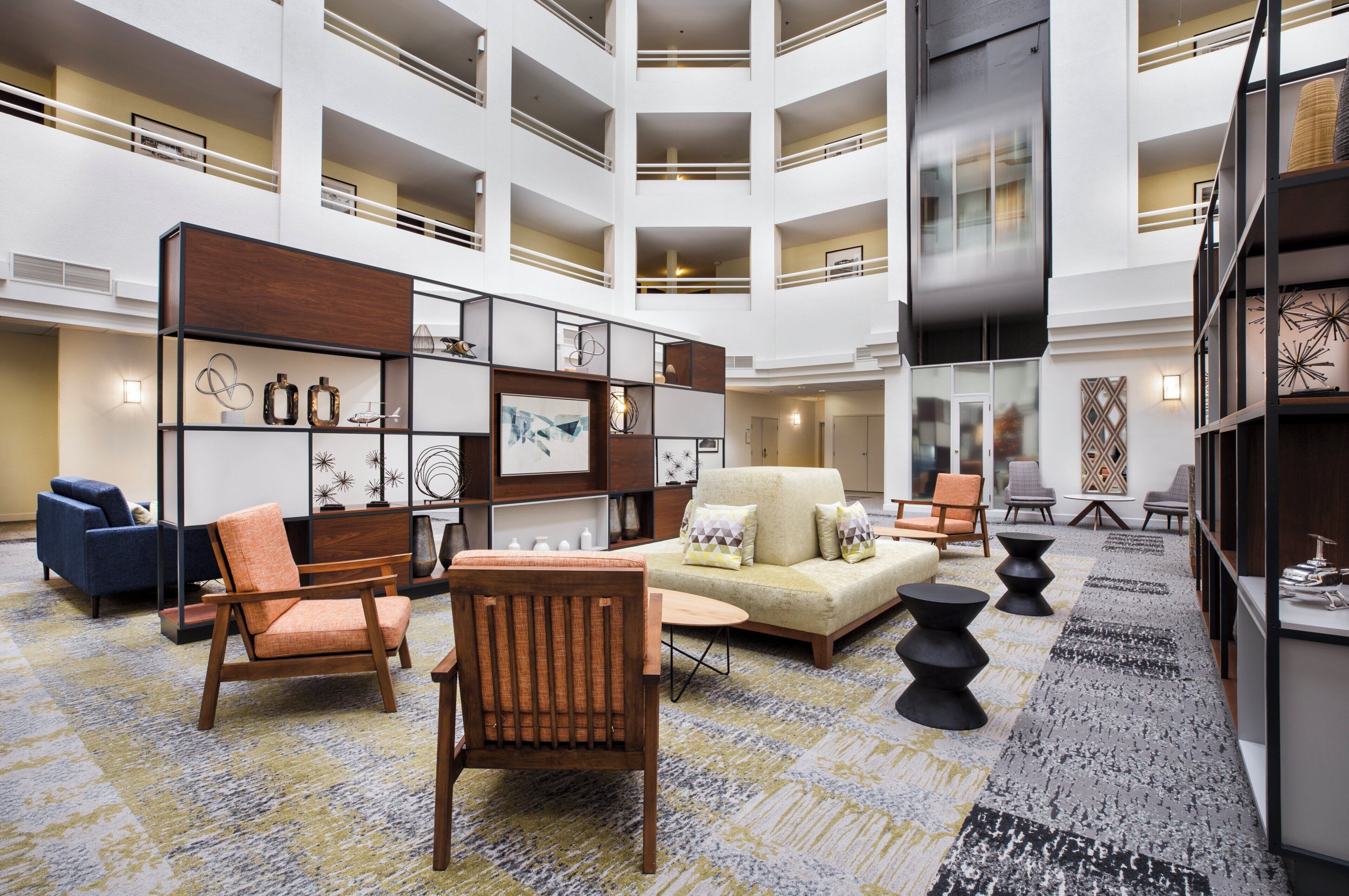 A spacious lobby with a high ceiling, multiple balconies, and a central seating area with sofas and chairs.