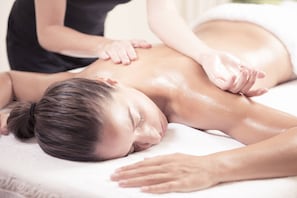 A person receiving a back massage on a white massage table.