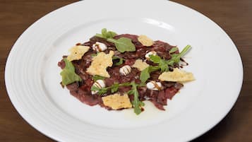 A white plate with a dark-colored food dish, garnished with green leaves and croutons.