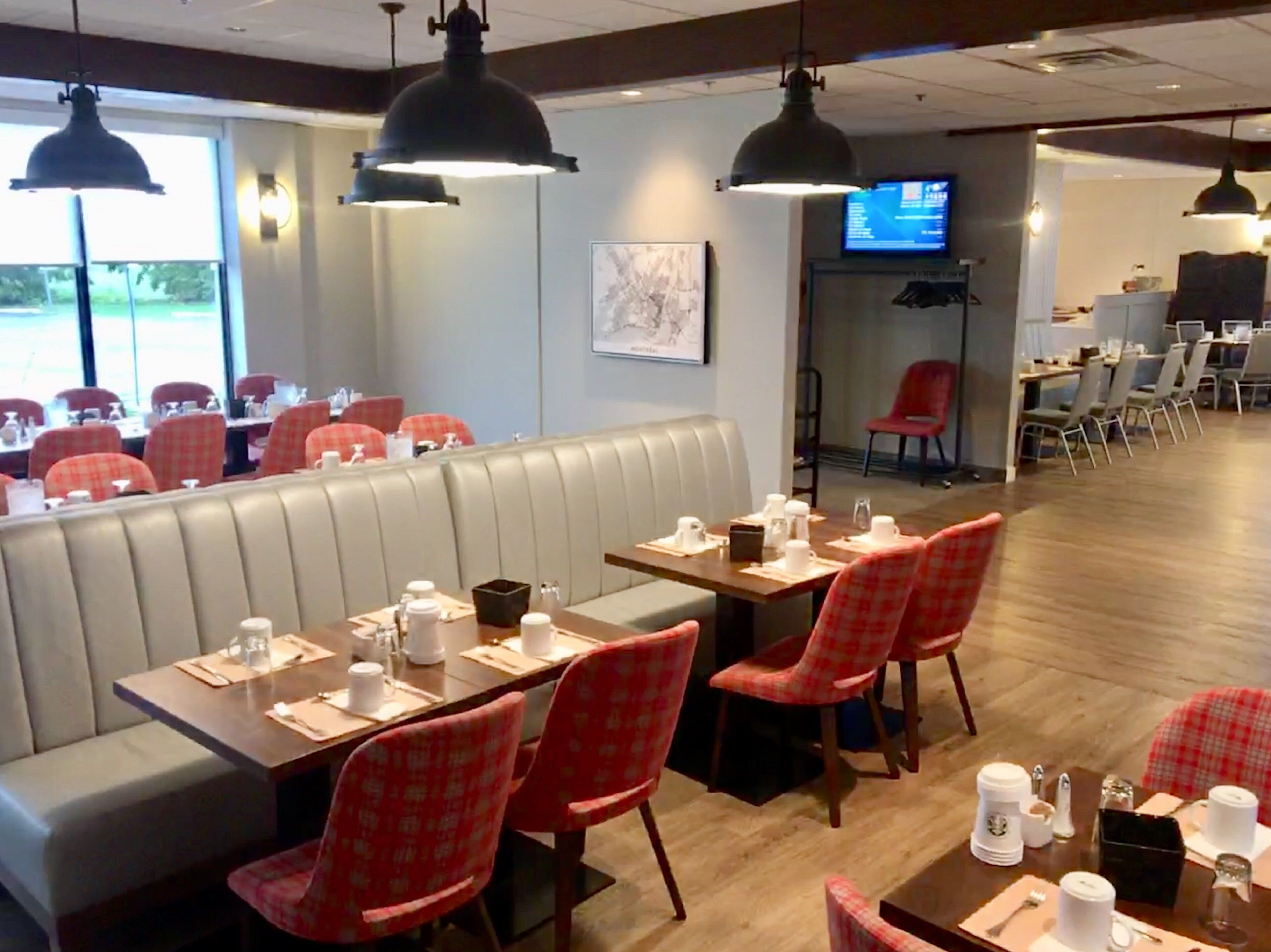 A restaurant with booths, red checkered chairs, and a wooden table with white cups and napkins.