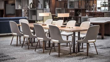 A modern dining area with a long table, six chairs, and two lamps.