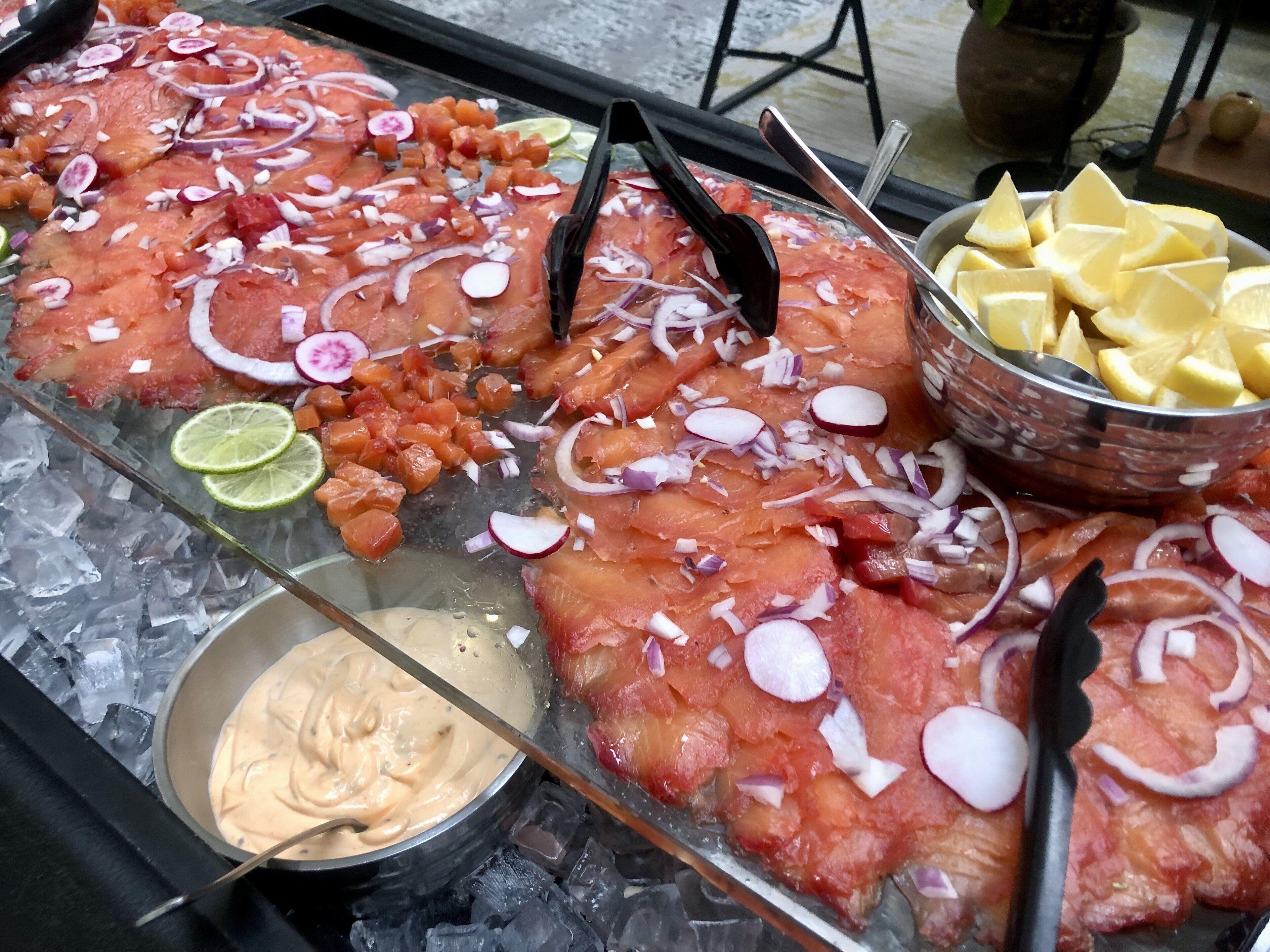 Une présentation de saumon cru sur de la glace, agrémenté de quelques garnitures, et un bol de sauce à côté.