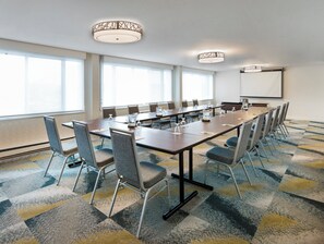 A conference room with a long table, chairs, a projector screen, and large windows. - Holiday Inn Montreal Longueuil by IHG (Longueuil)