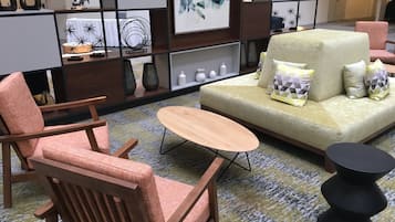 Una sala moderna con un sofá, dos sillones, una mesa baja y una mesita auxiliar negra.
