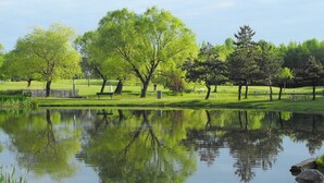 A serene park with a pond, benches, and trees. - Holiday Inn Montreal Longueuil by IHG (Longueuil)
